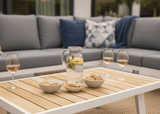 Aluminium loungeset 6-persoons wit frame met drank en snacks op een houten tafel in een moderne tuin.