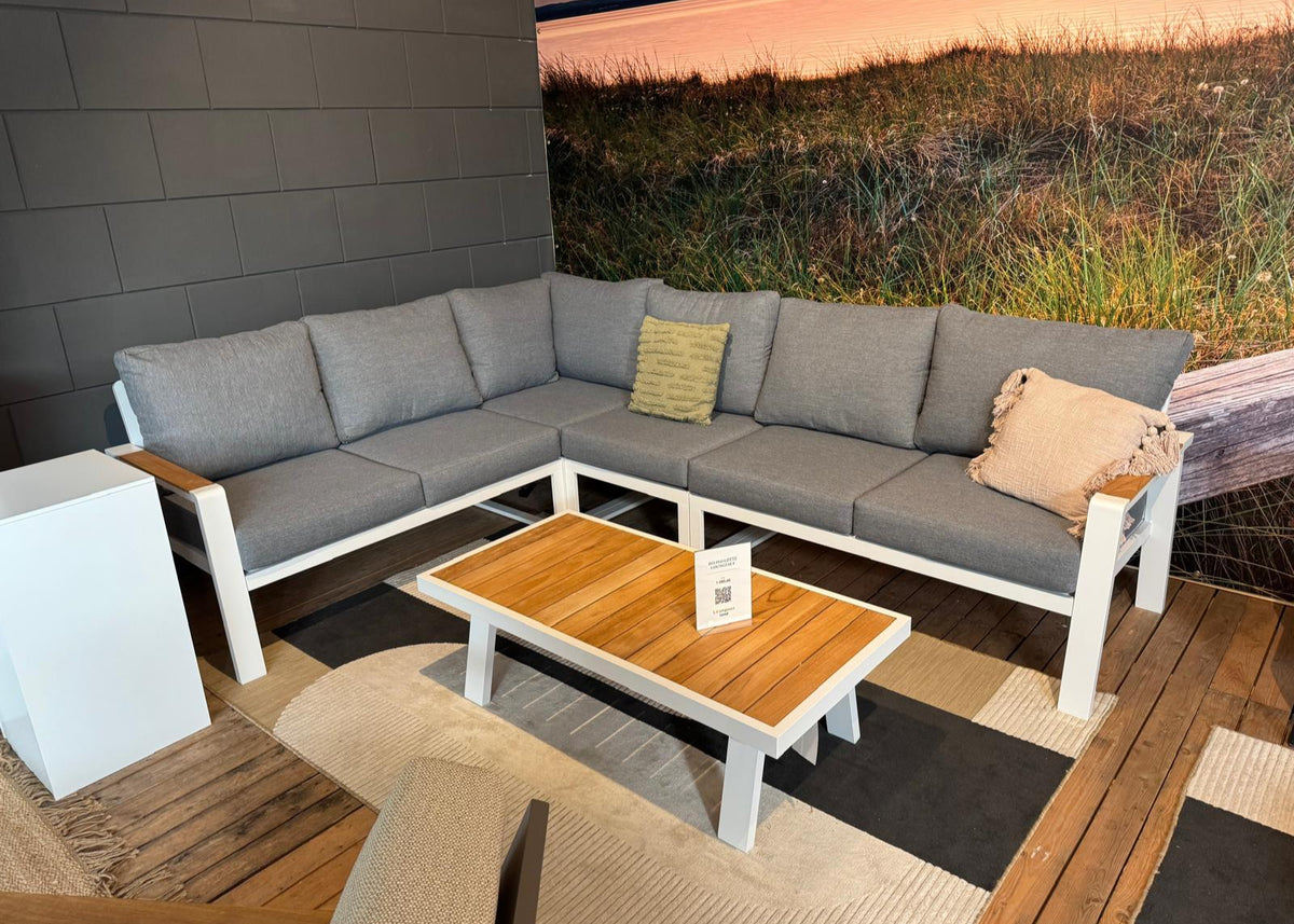 Aluminium loungeset 6-persoons wit frame met grijze kussens en houten tafel in showroom.