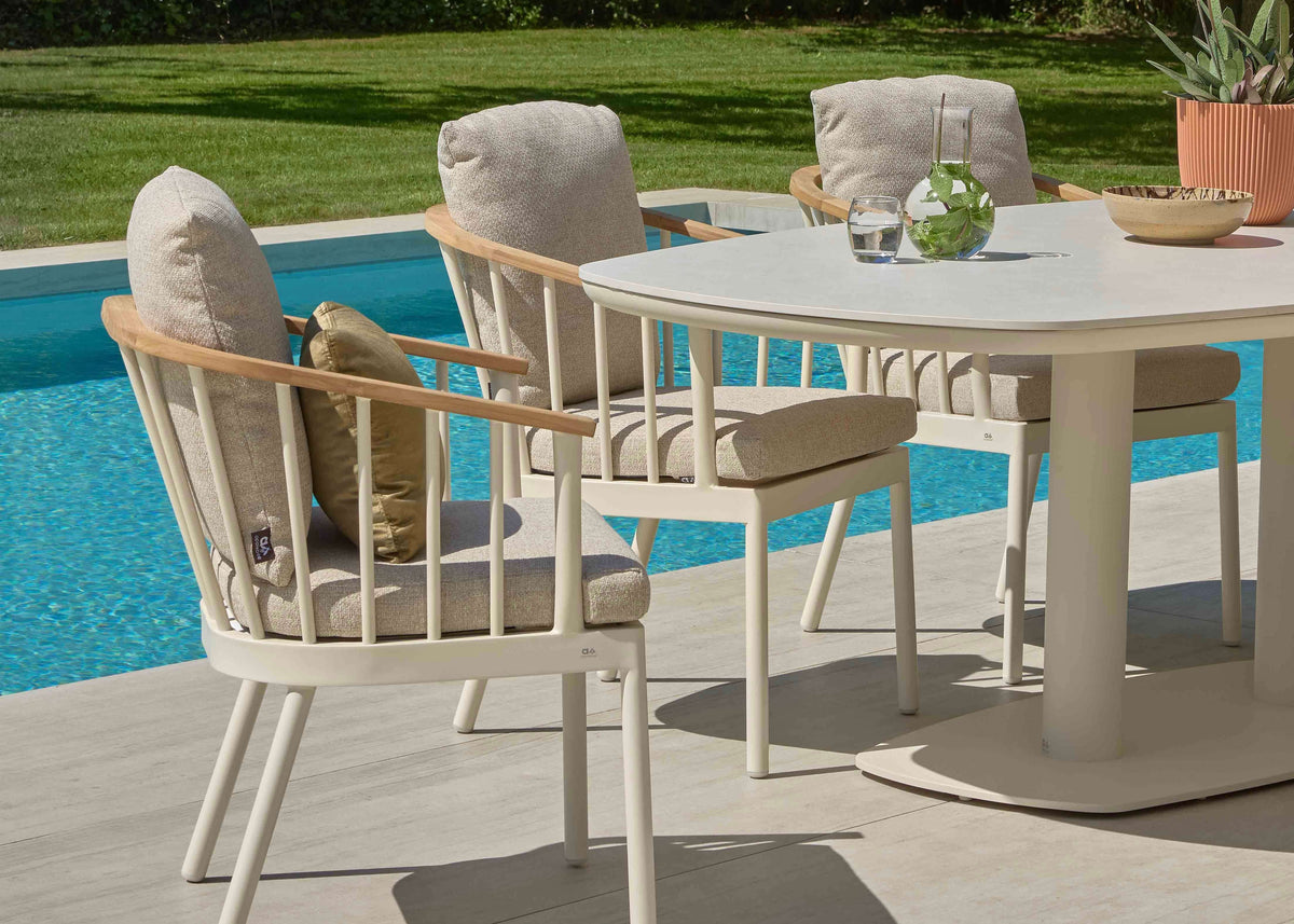 Apple Bee Zanzibar Dining Tuintafel 220 cm Cintered Stone Oyster met stoelen naast een zwembad.